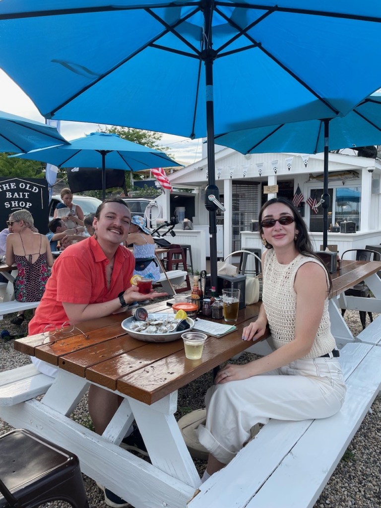 Docker Clark and Shelby McClelland sitting at a picnic table with food and drink in Greenport, NY.
